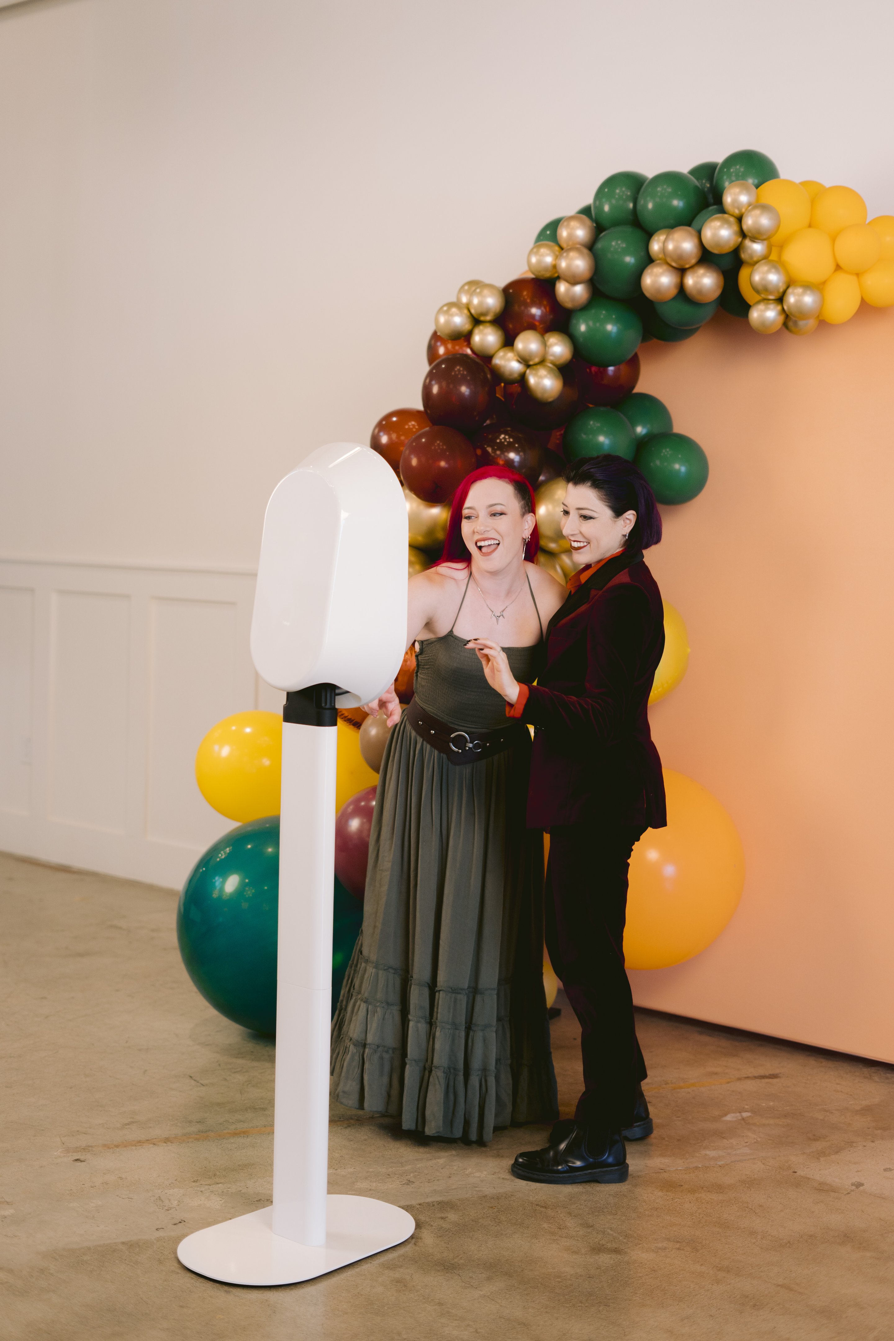 Two guests at the booth beside a balloon garland