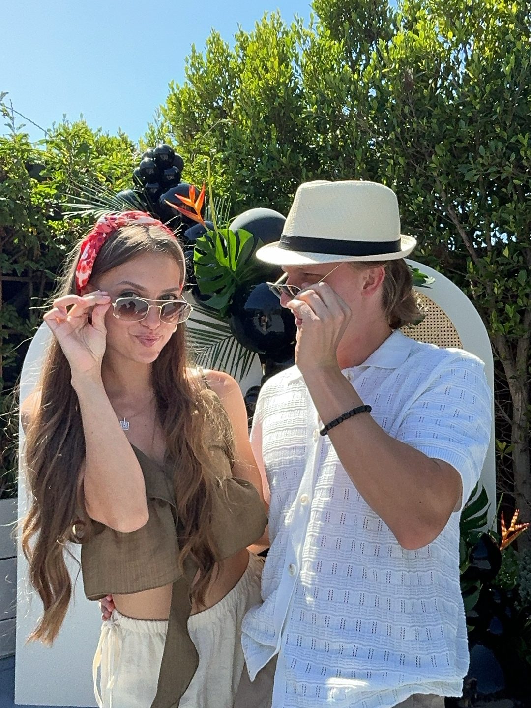 Two guests wearing sunglasses and a hat from the prop box