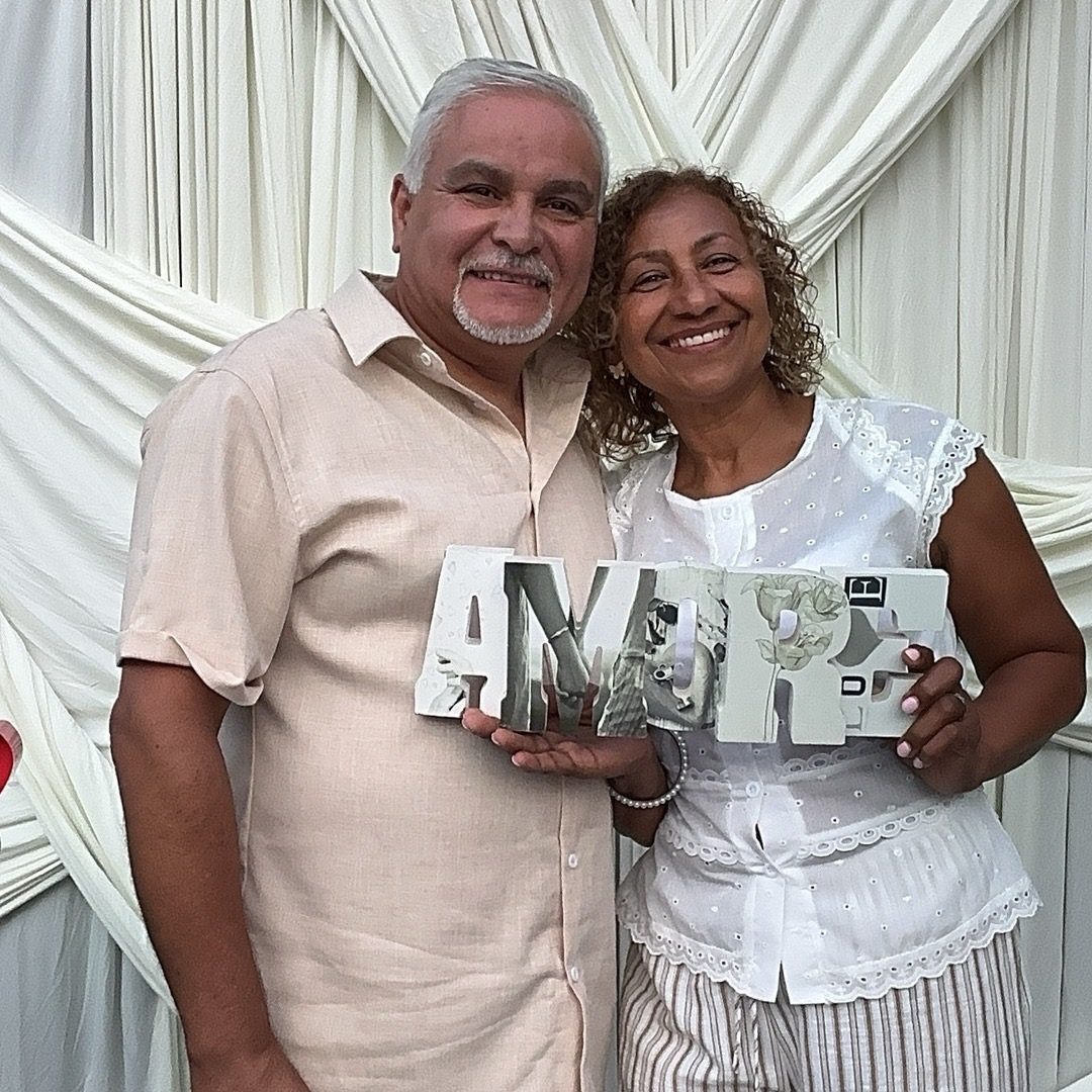 A couple holding letter props in front of an ivory draped backdrop
