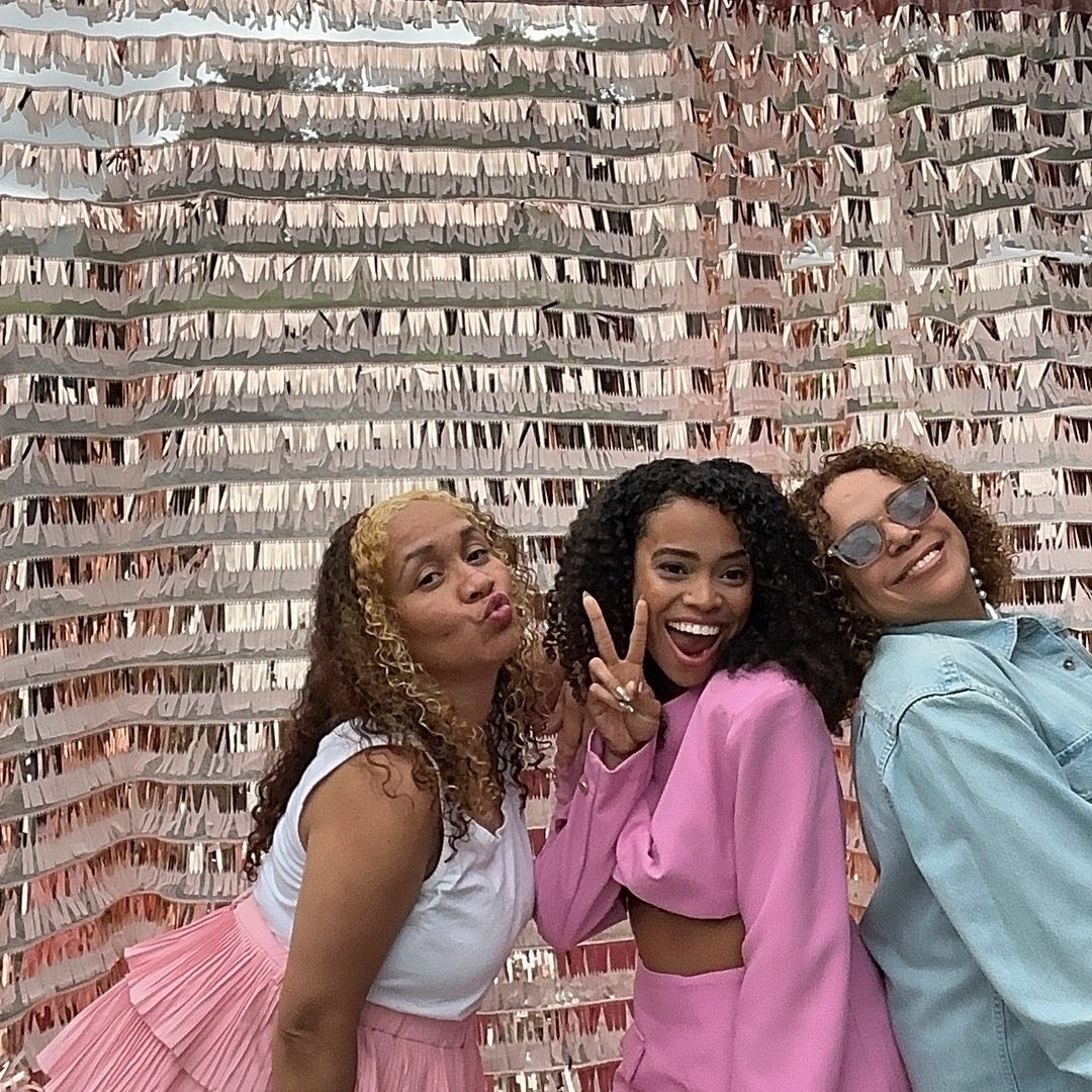 Guests in pink posing at a bridal shower in front of a fringe backdrop
