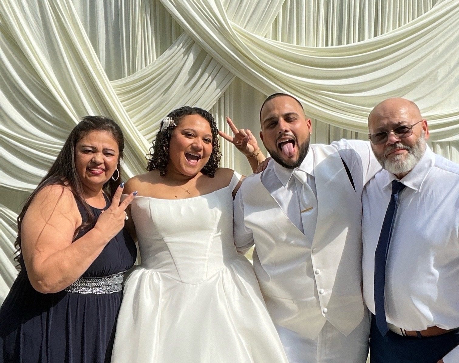 A bride and her guests gathered into one frame in front of ivory draping