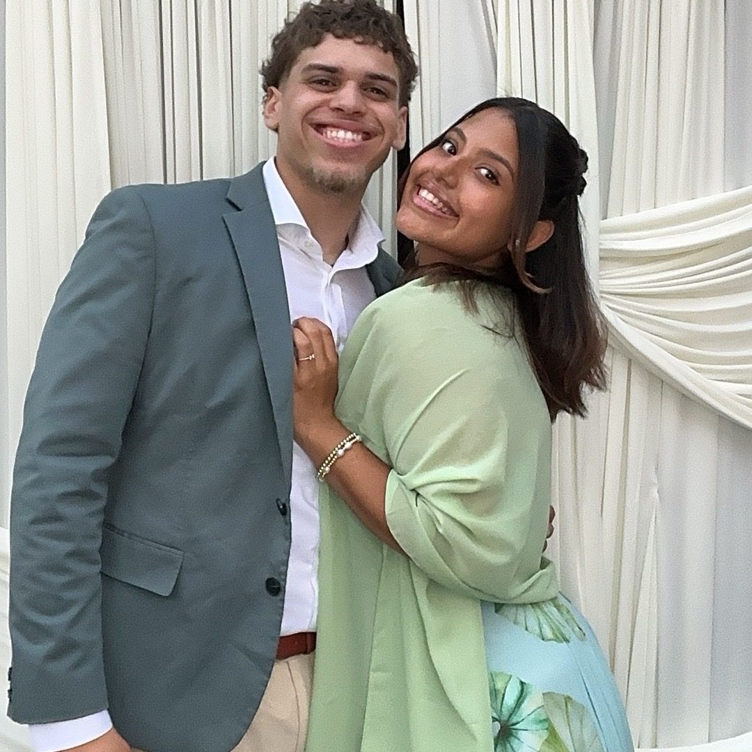 A couple holding each other in front of an ivory draped backdrop